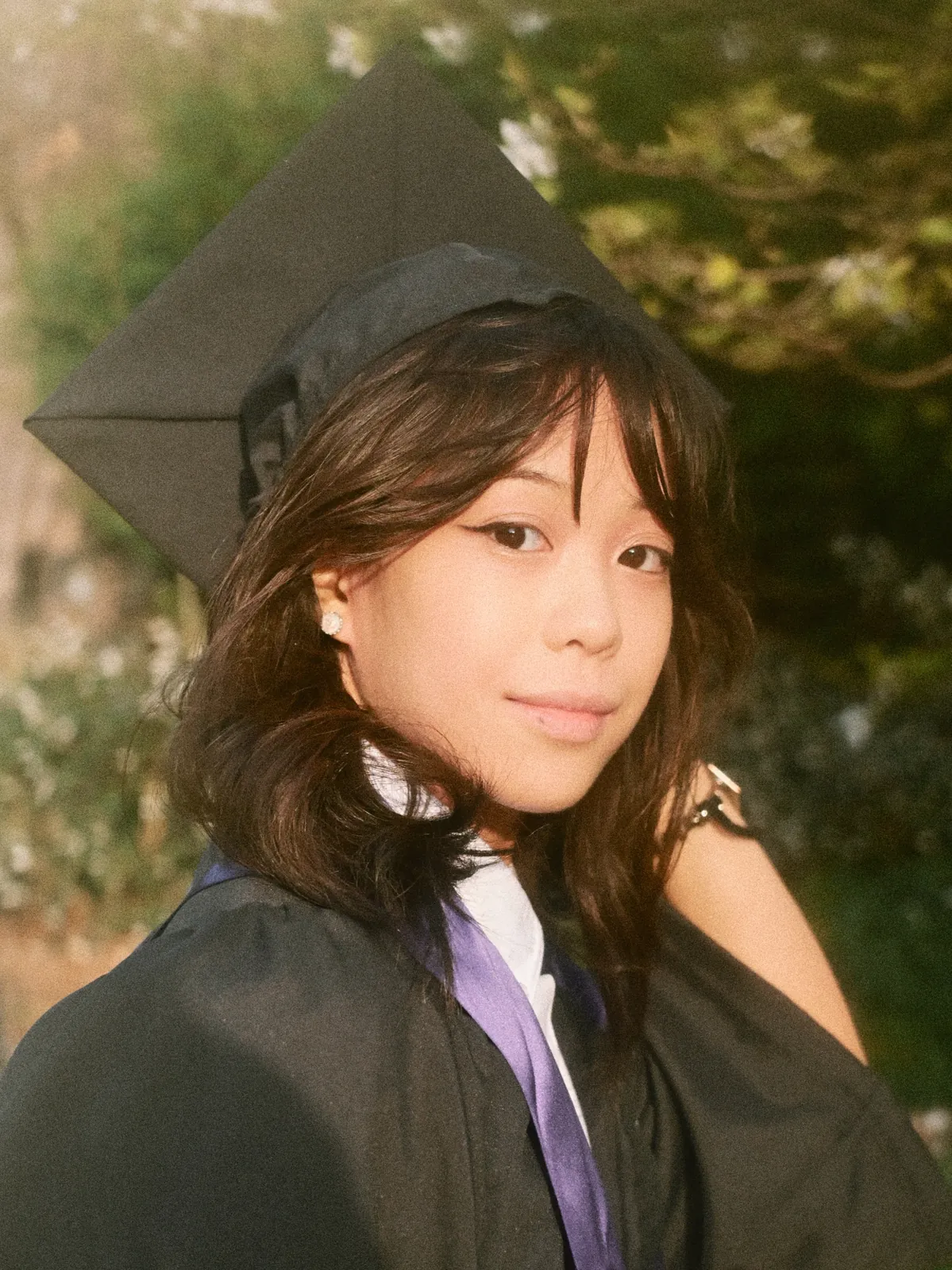 UW Graduate sitting on campus stairs, cap and gown portrait