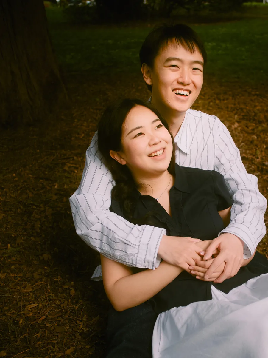 Laughing couple outdoors backlit by warm sun, engagement session