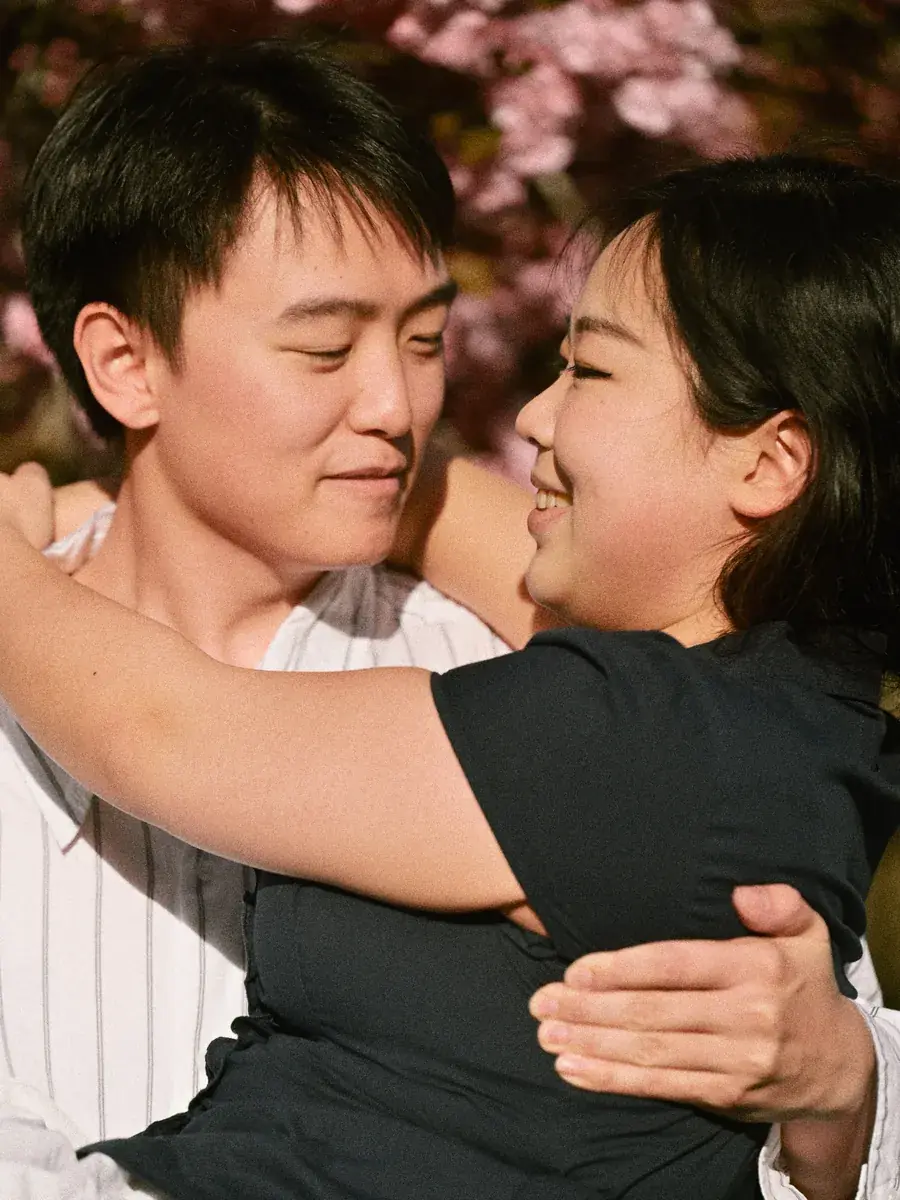 Couple embracing warmly under blooming cherry blossoms