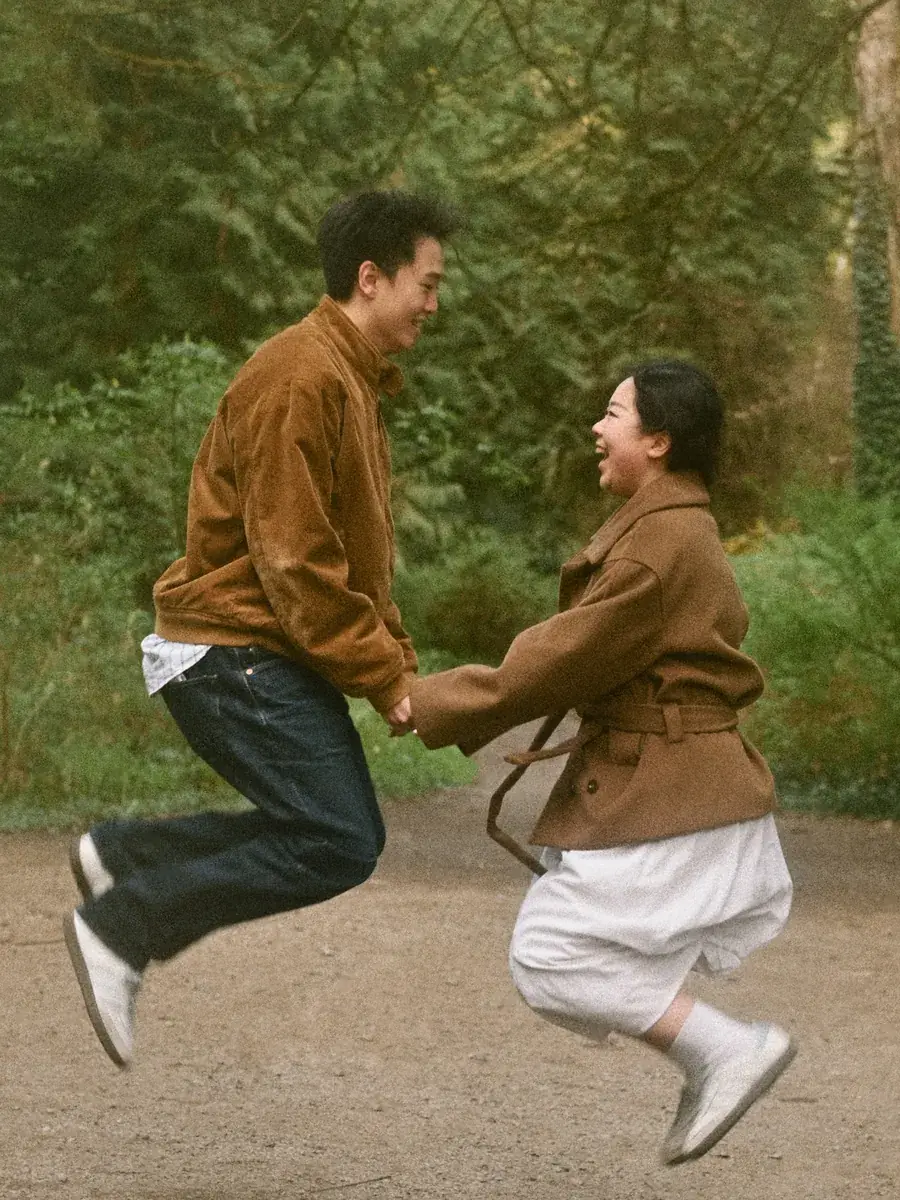 Couple laughing and jumping together on a wooded Seattle path