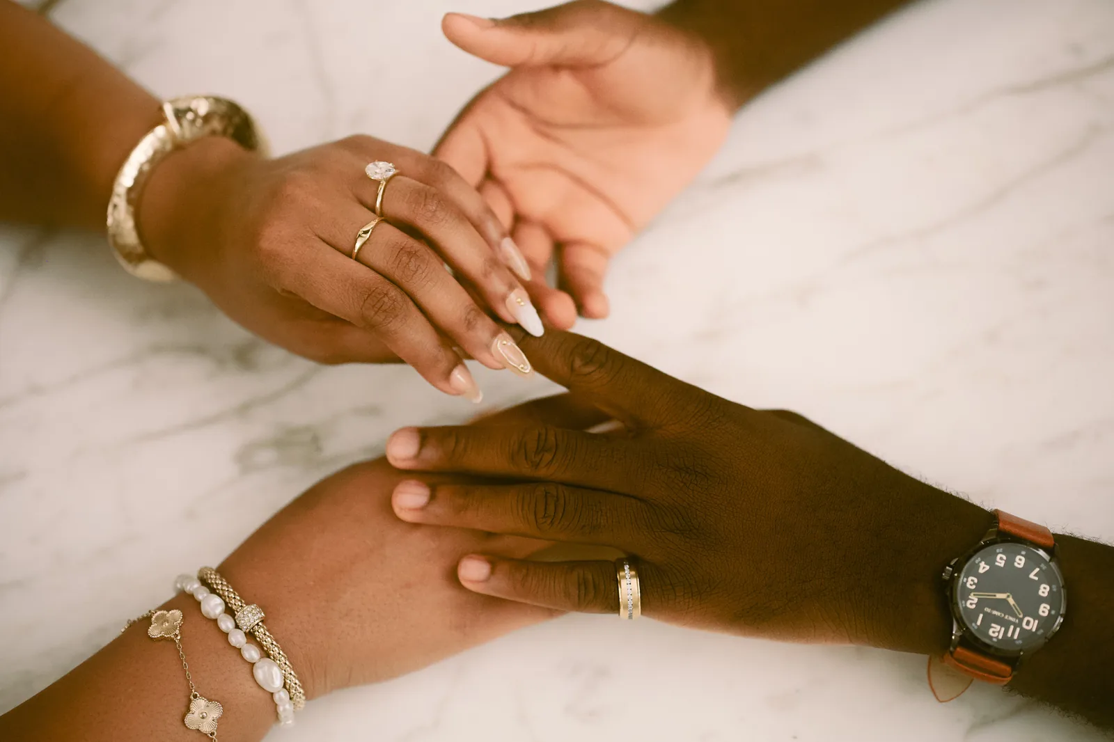 Close-up of an engaged couple holding hands and showing their rings