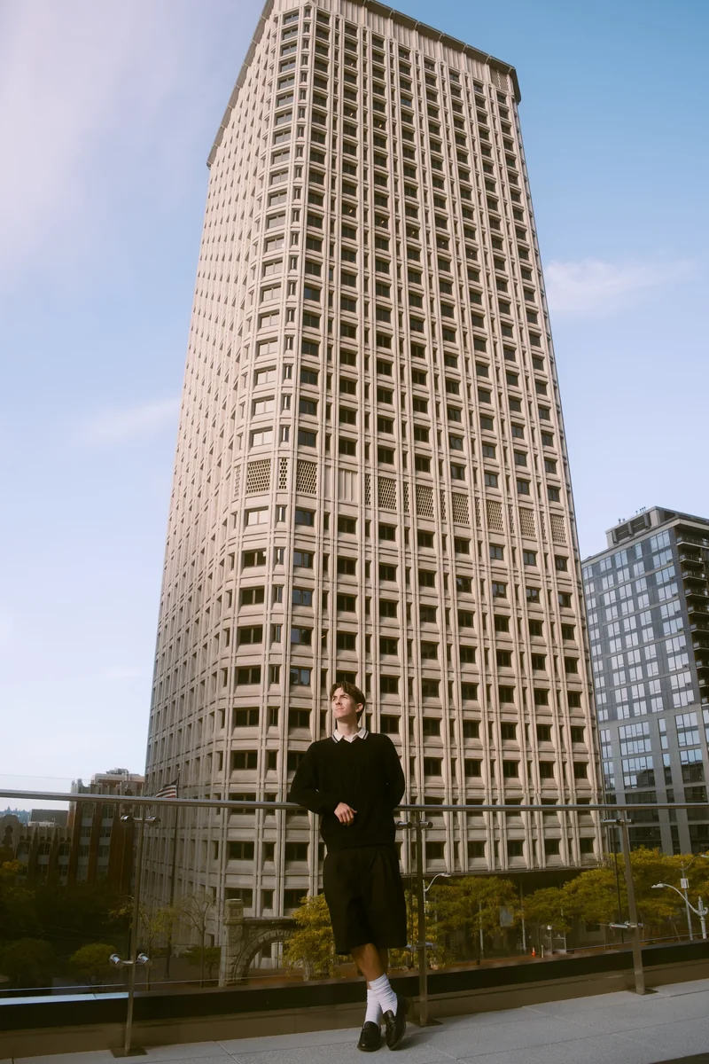 Senior standing on a rooftop beside a tall stone-faced tower in Seattle