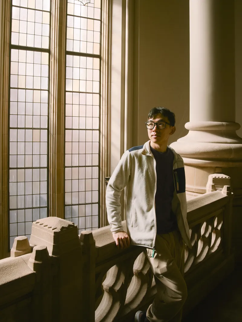 Collegiate senior portrait on Suzzallo Library grand stone staircase with gothic arched window
