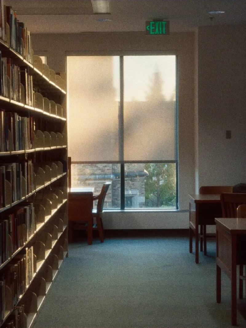 Suzzallo Library의 높은 책장 사이로 이어지는 조용한 통로