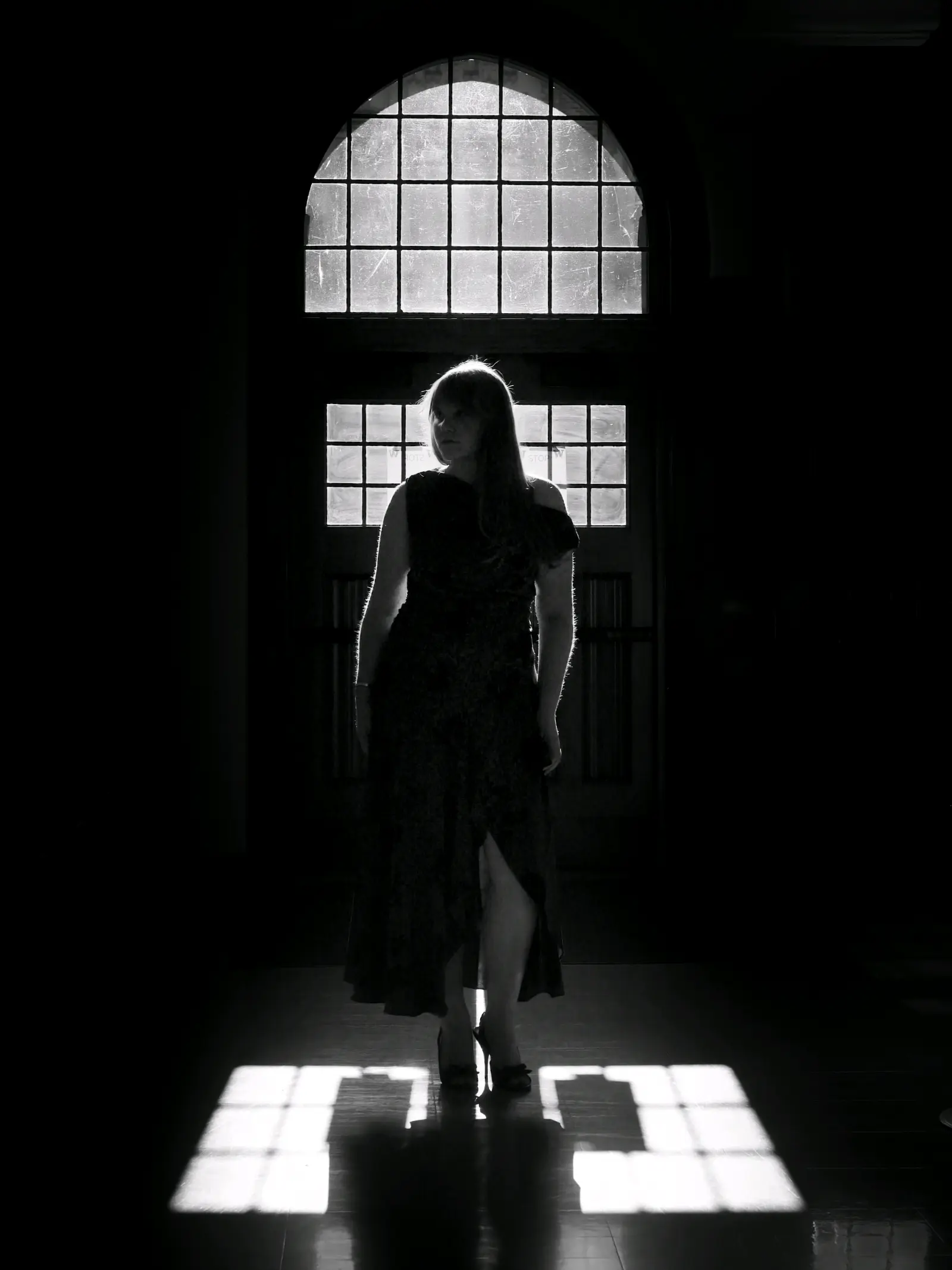Senior portrait silhouetted against a tall arched window